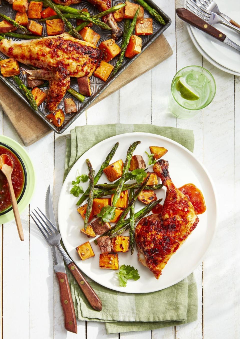 sweet and spicy chicken with roasted sweet potatoes and asparagus on a white plate with silverware