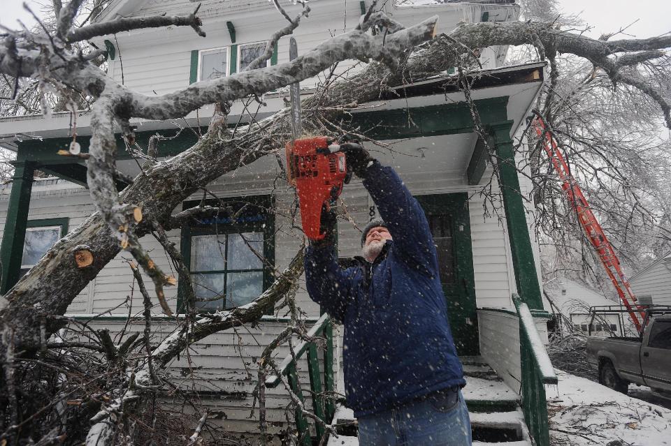 Tom Jandl removes branches from a fallen tree on his rental property at the corner of 13th Street and Prairie Avenue Wednesday, April 10, 2013 in Sioux Falls, S.D. (AP Photo/Argus Leader, Jay Pickthorn) NO SALES