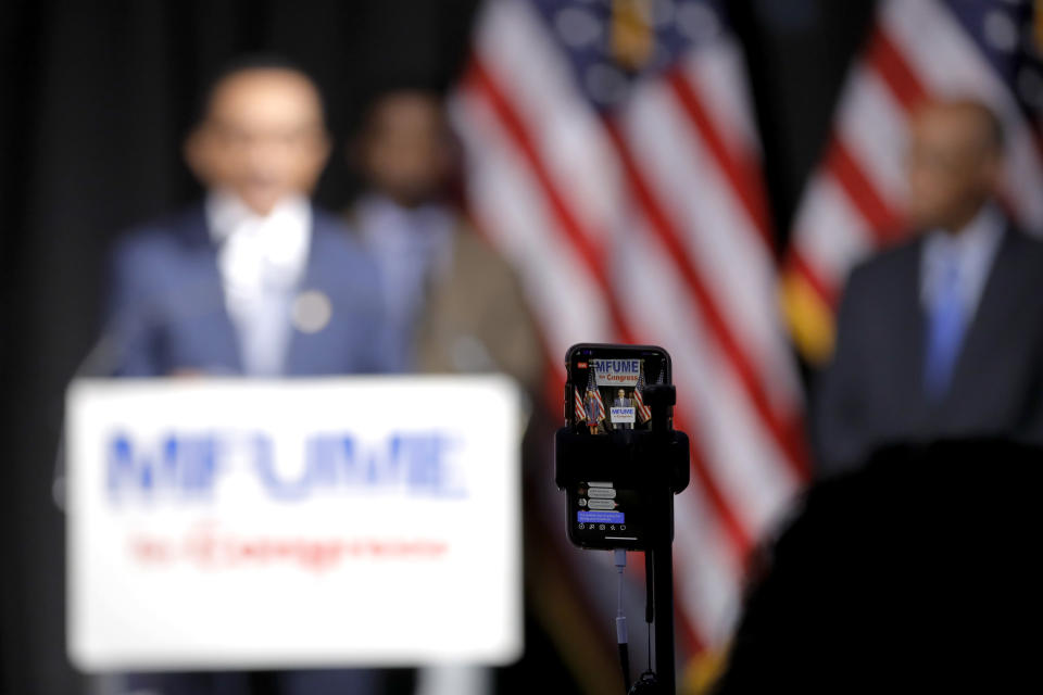 A cellphone is used for a Facebook Live stream as Democrat Kweisi Mfume, back left, addresses reporters at an election night news conference at his campaign headquarters after he won the 7th Congressional District special election, Tuesday, April 28, 2020, in Baltimore. Mfume defeated Republican Kimberly Klacik to finish the term of the late Rep. Elijah Cummings, retaking a Maryland congressional seat Mfume held for five terms before leaving to lead the NAACP. All voters in the 7th Congressional District were strongly urged to vote by mail because of the coronavirus pandemic. The seat came open after Cummings died in October. (AP Photo/Julio Cortez)