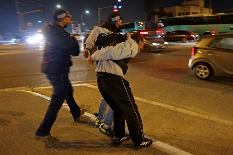 Las fuerzas de seguridad israelíes detienen a un palestino en el campo de refugiados de Shuafat en el este de Jerusalén el 28 de enero de 2023 mientras los israelíes protestan tras dos ataques perpetrados por palestinos. (Foto de AHMAD GHARABLI / AFP)