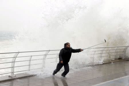 A man takes a selfie by a crashing wave on Beirut's Corniche, a seaside promenade, as high winds sweep through Lebanon during a storm in this February 11, 2015 file photo. REUTERS/Mohamed Azakir/Files