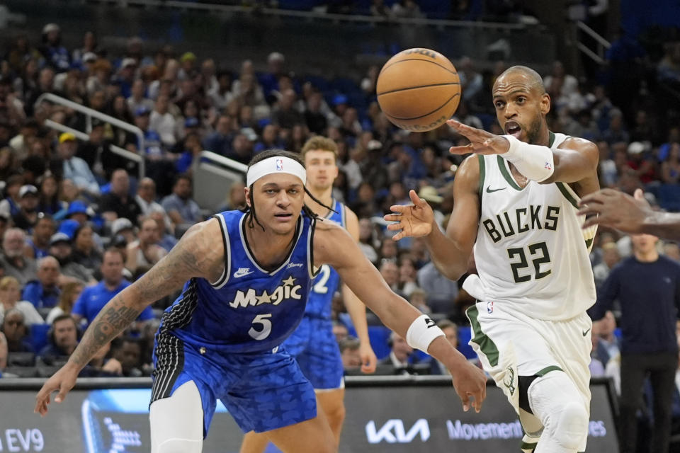 El escolta de los Bucks de Milwaukee Khris Middleton (22) pasa la bola ante el escolta del Magic de Orlando Paolo Banchero (5), durante la primera mitad del juego de baloncesto de la NBA, el domingo 14 de abril de 2024, en Orlando, Florida. (AP Foto/John Raoux)