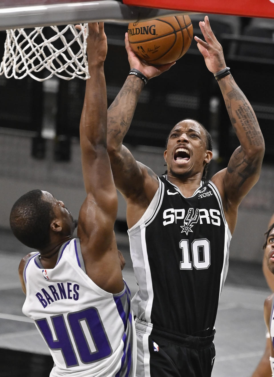 San Antonio Spurs' DeMar DeRozan (10) shoots against Sacramento Kings' Harrison Barnes during the first half of an NBA basketball game Wednesday, March 31, 2021, in San Antonio. (AP Photo/Darren Abate)