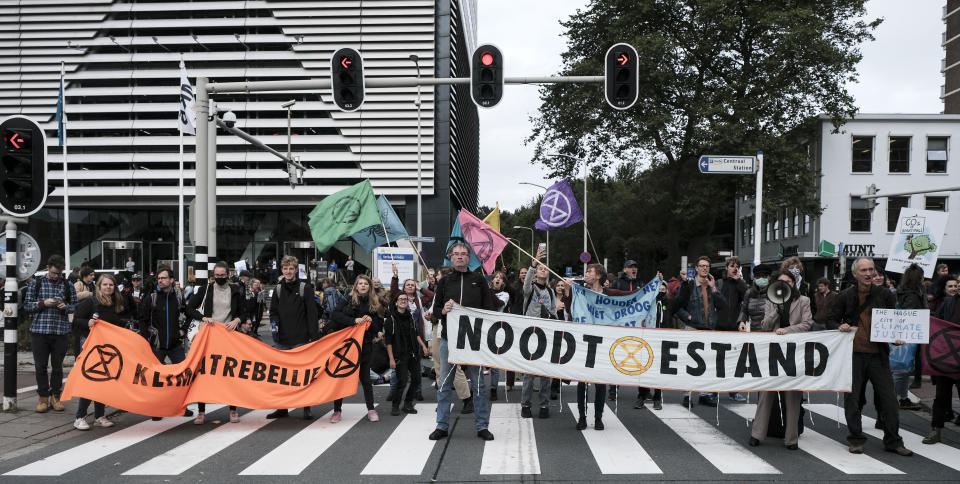 Protestors from climate activism group of Extinction Rebellion block a busy intersection near the temporary home of the Dutch parliament in The Hague, Netherlands, Monday, Oct. 11, 2021. The group says it plans a series of demonstrations in the city throughout the week ahead of a major United Nations climate conference that opens Oct. 31, in Glasgow. (AP Photo/Patrick Post)