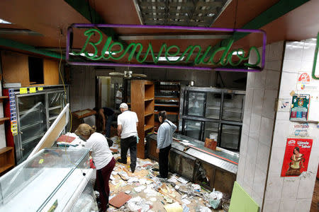 Trabajadores revisan los daños al interior de una panadería saqueada en Caracas, abr 20, 2017. Por segundo día consecutivo, miles de partidarios de la oposición salieron el jueves a las calles de Venezuela para protestar en contra del presidente Nicolás Maduro, a quien acusan de la grave crisis económica y de haber desvirtuado su Gobierno al convertirlo en una dictadura. REUTERS/Christian Veron