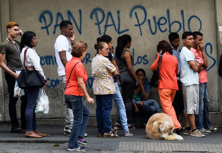 People queue outside a bakery in Caracas to buy bread which has become all but impossible to find at many Venezuelan bakeries