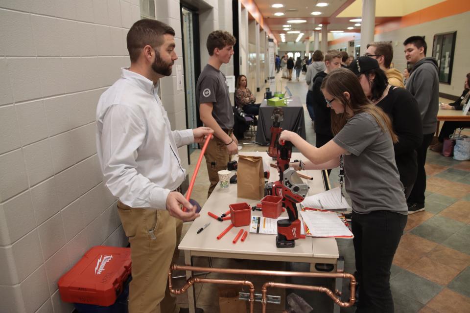 Andy Carver of Adrian Mechanical Services watches as Tecumseh High School freshman Rhea McGrew cuts a piece of tubing during the Career Exploration Fair Wednesday at the school.