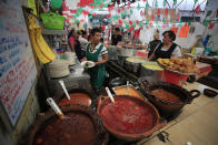 In this Sept. 10, 2019 photo, Maribel Sanchez carries a chile en nogada prepared for a diner at El Sabor, a family-owned restaurant inside Juarez Market that for decades has been serving up chiles en nogada in the weeks leading up to Mexico's independence celebrations, in Mexico City. Although the 200 peso ($10.50) price tag at El Sabor is half that at high end restaurants, the traditional ingredients and hours of labor that go into making the sweet and salty dish mean it is still the priciest item on their menu, a seasonal treat for fans of the dish. (AP Photo/Rebecca Blackwell)