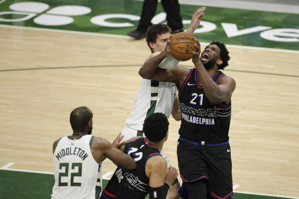 Philadelphia 76ers' Joel Embiid (21) drives to the basket next to Milwaukee Bucks' Brook Lopez during the second half of an NBA basketball game Thursday, April 22, 2021, in Milwaukee. (AP Photo/Aaron Gash)