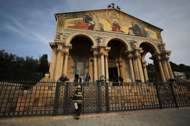An Israeli firefighter stands outside the Church of All Nations next to the Garden of Gethsemane after a man tried to set a fire inside the Church