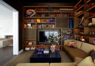 <p>Chaleureuse, la bibliothèque en bois qui fait le tour de l’espace permet de créer une vraie rupture avec le salon malgré la proximité. </p>
