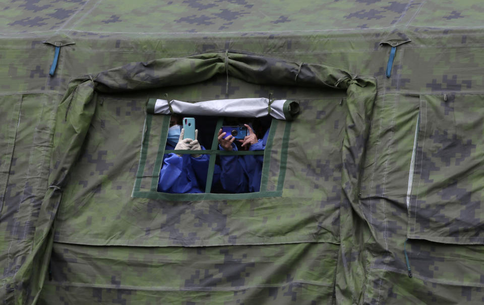 Healthcare workers take pictures of Ecuadorian President Lenin Moreno attending the COVID-19 vaccination campaign for soldiers at the Epiclachima Military Fort in Quito, Ecuador, Thursday, April 8, 2021. (AP Photo/Dolores Ochoa)