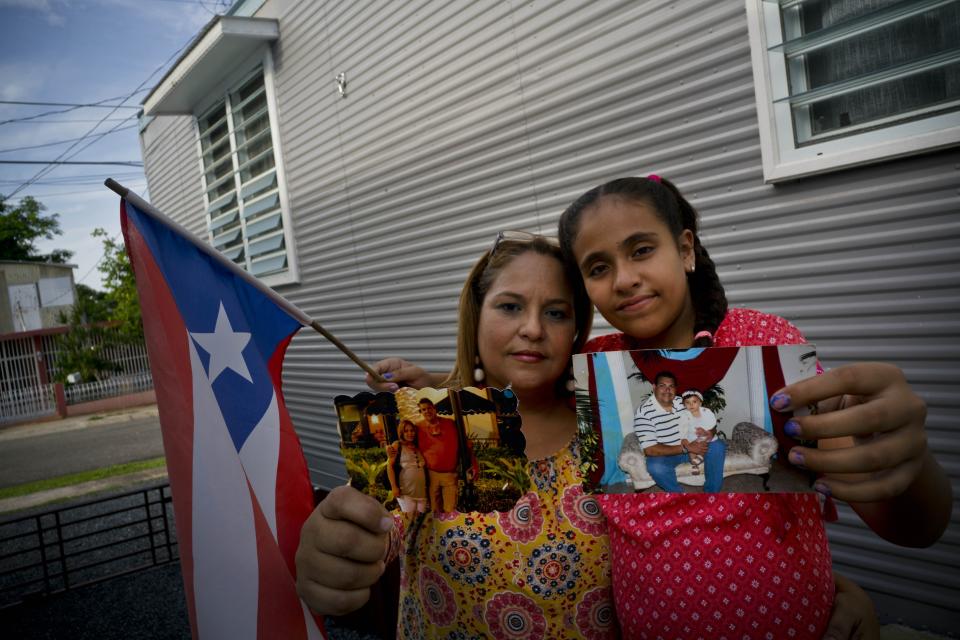 In this Sept. 5, 2018 photo, Lady Diana Torres, left, and her daughter Paula Nicole Lopez, pose with photos of their late husband and father Orlando Lopez Martinez, in Aguadilla, Puerto Rico. Lopez, who died at age 48 on Oct. 10, developed diabetes when he was 11, forcing him to begin dialysis. The center where he received dialysis shut down after Hurricane Maria hit, and after missing some treatments over more than a week, the center rationed his dialysis, according to friends and family. The official cause of death was a heart attack brought on by kidney disease. (AP Photo/Ramon Espinosa)