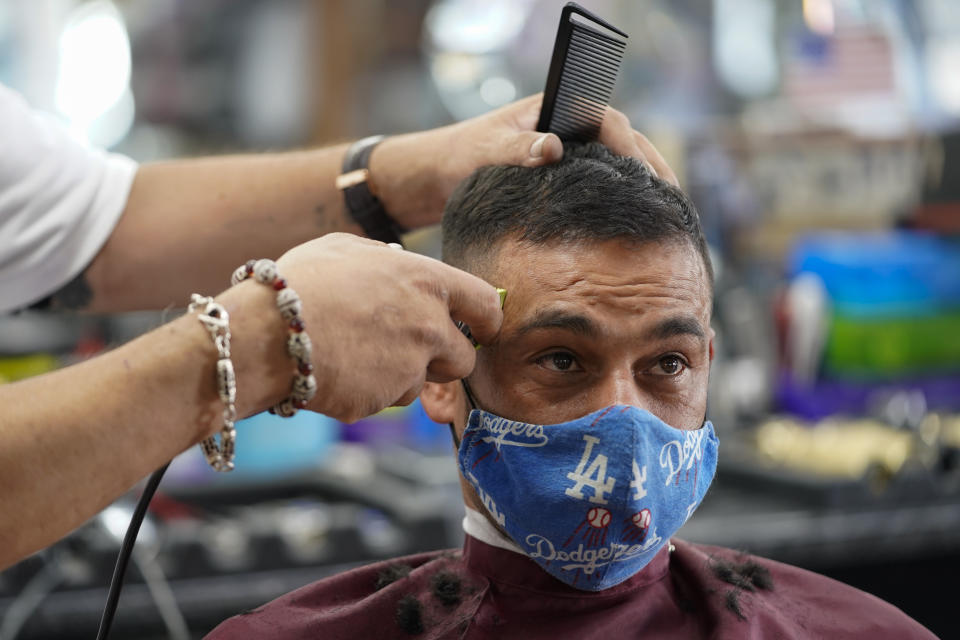 Edgar Gomez has his hair cut by George Garcia, owner of George's Barber Shop, Tuesday, July 14, 2020, in San Pedro, Calif. Gov. Gavin Newsom this week ordered that indoor businesses like salons, barber shops, restaurants, movie theaters, museums and others close due to the spread of COVID-19. (AP Photo/Ashley Landis)