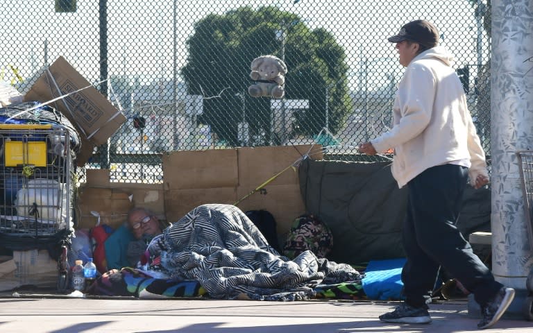 A pedestrian walks past a homeless man living on the street in Los Angeles on December 2, 2015