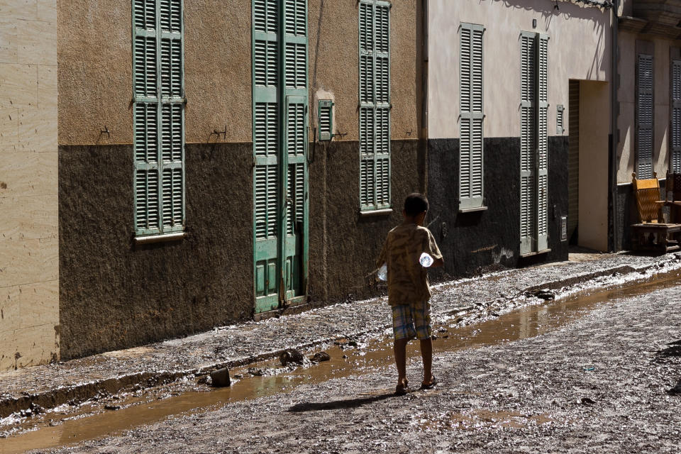 A boy walk along the street after flooding in Sant Llorenc, Mallorca, Spain, Thursday, Oct. 11, 2018. Spanish rescuers have found the bodies of a German couple that went missing after a destructive flash flooding that killed at least 10 more earlier this week in Mallorca and are still looking for a missing child. (AP Photo/Francisco Ubilla)