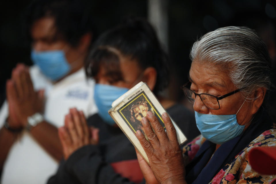 Mourners wearing protective face masks pray during the cross raising ceremony for Luz Maria Gonzalez, in the family home in Valle de Chalco, on the outskirts of Mexico City, Friday, July 3, 2020. Gonzalez, 56, who had long suffered from asthma, diabetes, and hypertension, died two days after her 29-year-old son, who was hospitalized for breathing problems and a cough before dying of complications said to be related to pneumonia and undiagnosed diabetes. (AP Photo/Rebecca Blackwell)