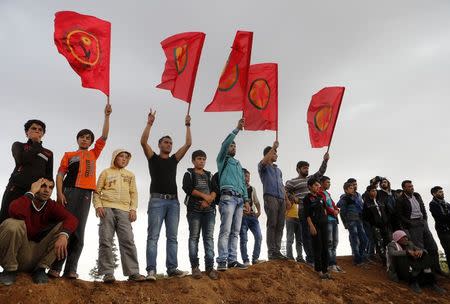 Kurds gesture and hold flags as they attend the funeral of the four Kurdish women fighters killed during clashes against Islamic State fighters in Kobani, at a cemetery in the southeastern town of Suruc, Sanliurfa province, October 14, 2014. REUTERS/Umit Bektas