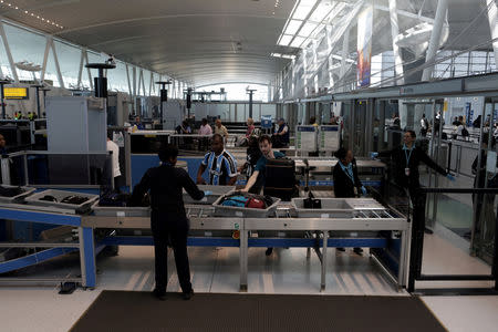 FILE PHOTO: Passengers scan their bags with Transportation Security Administration (TSA) employees at Terminal 4 of JFK airport in New York City, U.S., May 17, 2017. REUTERS/Joe Penney/File Photo