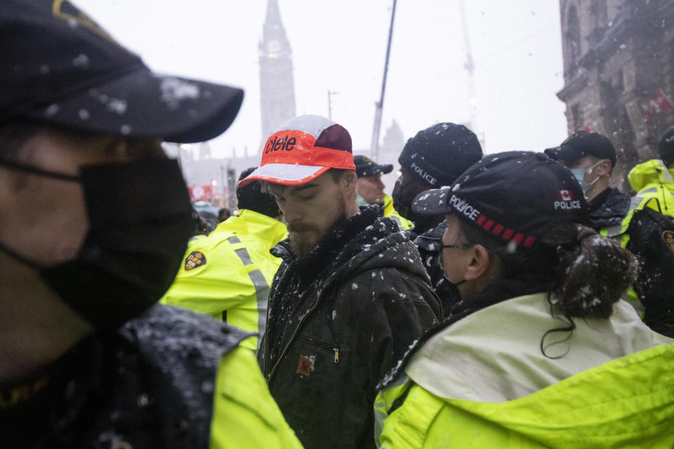 Police lead a protester towards a cruiser after making an arrest on Wellington Street, during an ongoing protest against COVID-19 measures that has grown into a broader anti-government protest, in Ottawa, Ontario, on Thursday, Feb. 17, 2022. (Justin Tang/The Canadian Press via AP)