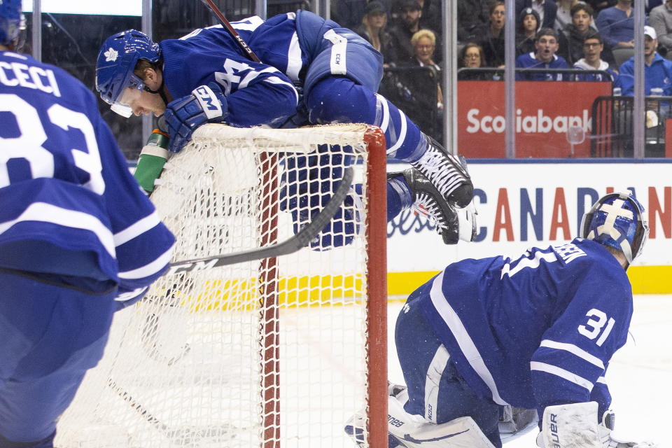 Toronto Maple Leafs defenseman Morgan Rielly (44) collides with the net behind goaltender Frederik Andersen (31) during the second period of the team's NHL hockey game against the Tampa Bay Lightning on Tuesday, March 10, 2020, in Toronto. (Chris Young/The Canadian Press via AP)