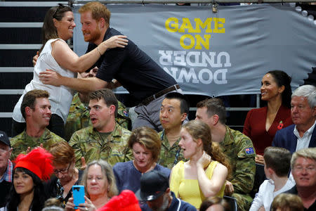 Britain's Prince Harry hugs a spectator as Meghan, Duchess of Sussex, looks on during the Invictus Games Sydney 2018 wheelchair basketball gold medal match at Quaycentre in Sydney, Australia October 27, 2018. REUTERS/Phil Noble