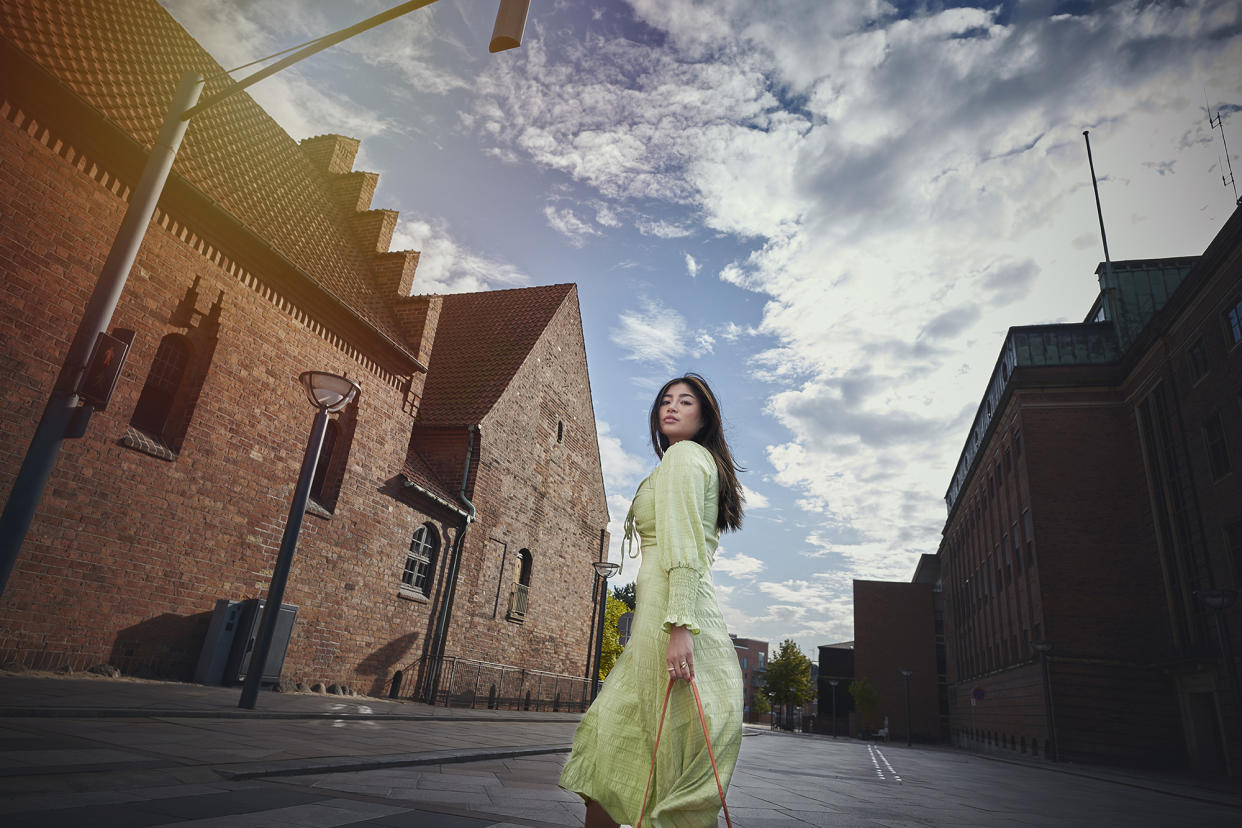 Model outdoors in city / street. Woman in green dress walking