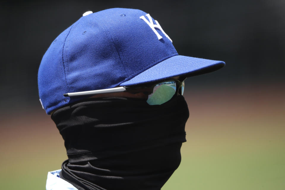 Kansas City Royals bench coach Pedro Grifol wears a mask as he watches baseball practice at Kauffman Stadium on Thursday, July 9, 2020, in Kansas City, Mo. (AP Photo/Charlie Riedel)