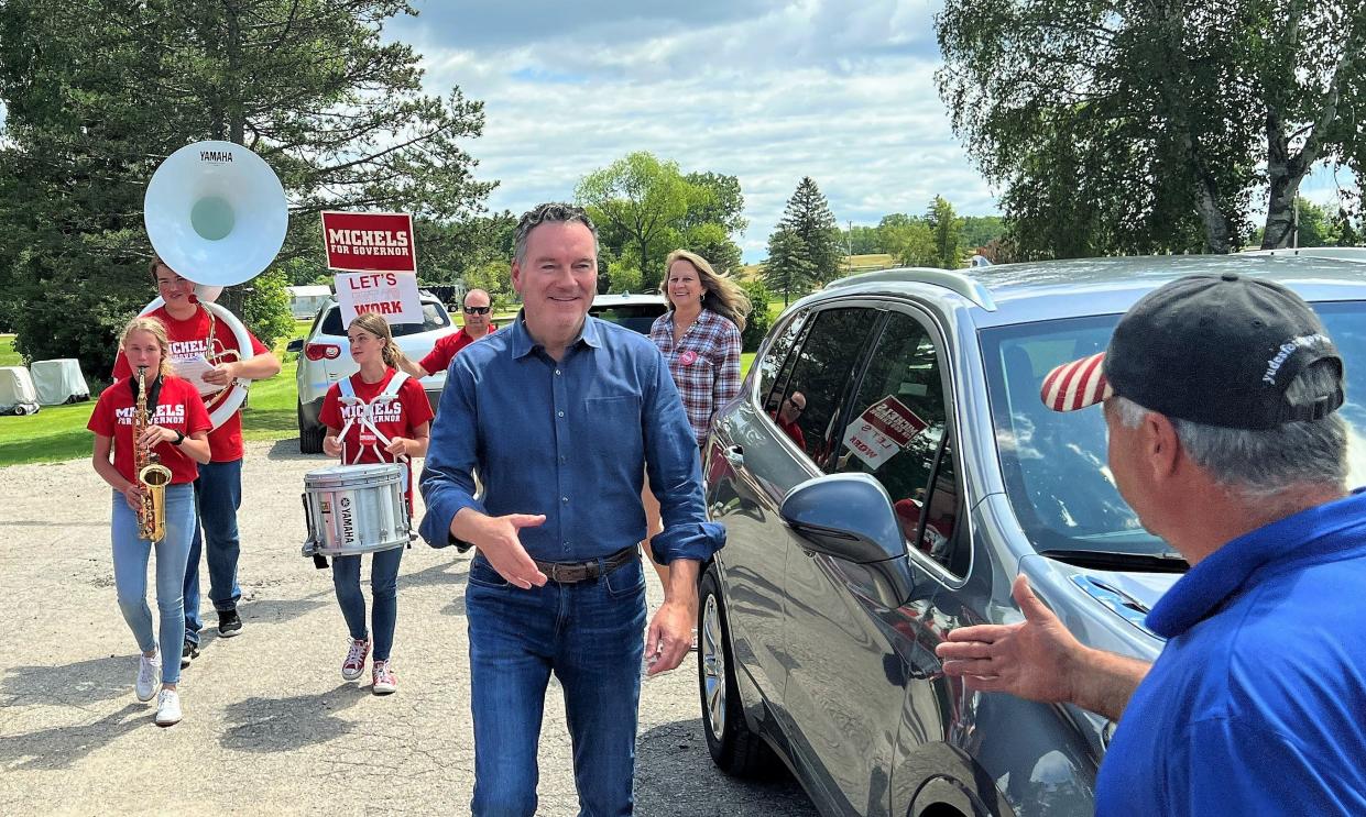 Making an entrance with a small marching band, Republican gubernatorial candidate Tim Michels is welcomed by owner Ken Sikora on Tuesday, July 12, to the Irish Greens Golf Course.