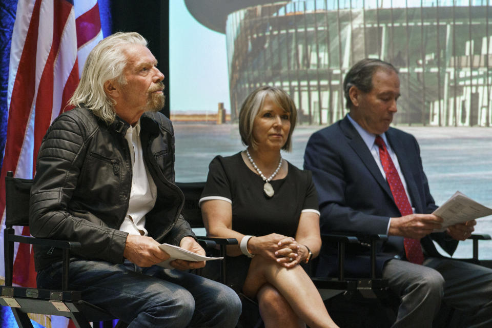 Virgin Galactic founder Richard Branson, left, New Mexico Gov. Michelle Lujan Grisham and U.S. Sen. Tom Udall wait to speak during an event at the state capital on Friday, May 10, 2019, in Santa Fe, N.M. Branson announced Friday that his company will begin shifting operations from California to a spaceport and specialized runway in the New Mexico desert in final preparations for commercial flights. (AP Photo/Craig Fritz)