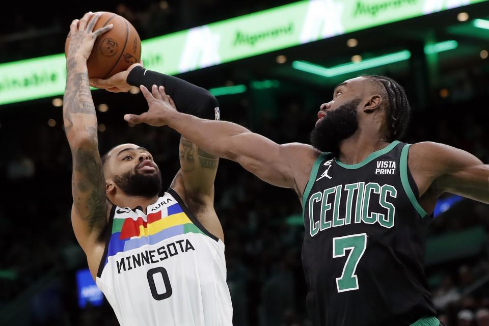 Minnesota Timberwolves' D'Angelo Russell (0) shoots against Boston Celtics' Jaylen Brown (7) during the first half of an NBA basketball game, Friday, Dec. 23, 2022, in Boston. (AP Photo/Michael Dwyer)