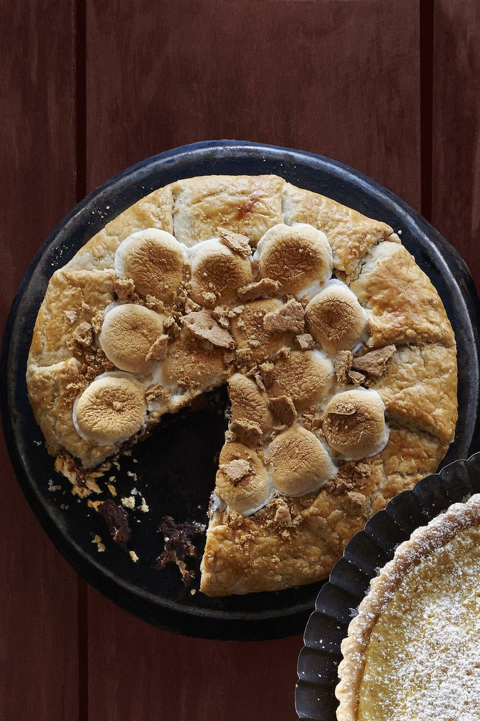 smores galette in a metal pie dish with toasted marshmallows and graham cracker pieces on top