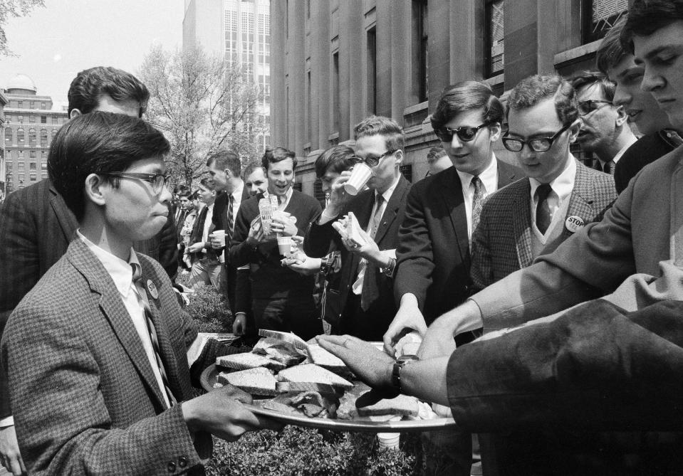 FILE - Columbia University students forming a blockade around Low Memorial Library on the New York City campus, eat sandwiches and drink milk while preventing food from being taken to student demonstrators inside, April 29, 1968. Later, friends of the student protesters were able to throw some food up to them. (AP Photo/Anthony Camerano, File)