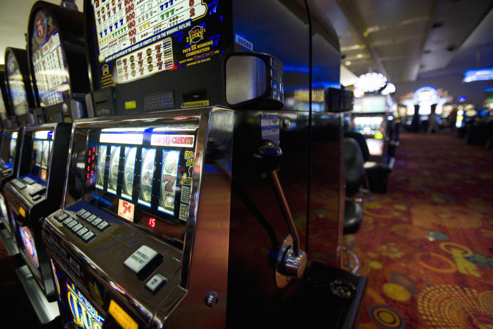 Row of slot machines in a casino with seats and gaming environment visible