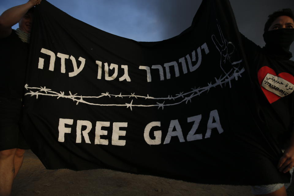 Israeli peace activists hold a banner during a protest on Israel Gaza border, Friday, Oct. 5, 2018. Writing in Hebrew reads "Free Gaza ghetto". (AP Photo/Ariel Schalit)