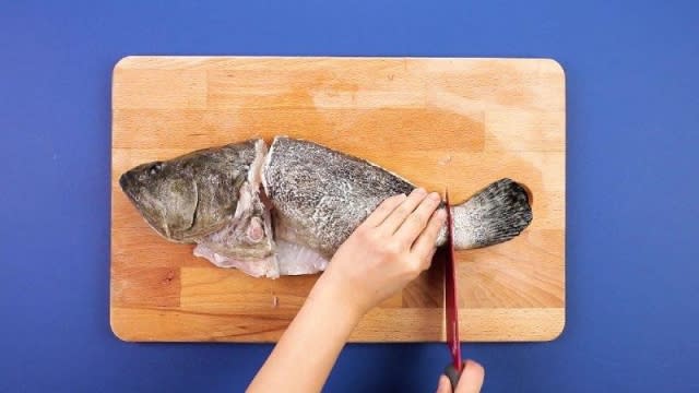 Cutting head and tail off grouper with a knife