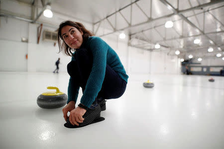 A Yazidi refugee from Kurdistan kneels on the ice as she learns the sport of the curling at the Royal Canadian Curling Club during an event put on by the "Together Project", in Toronto, March 15, 2017. REUTERS/Mark Blinch