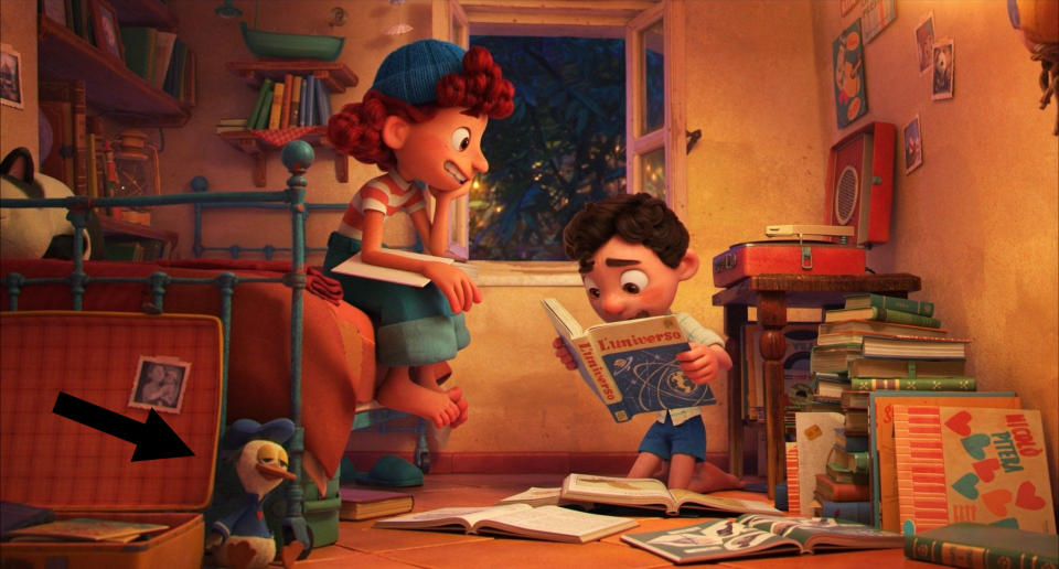 A girl and boy reading books in a room full of books and toys