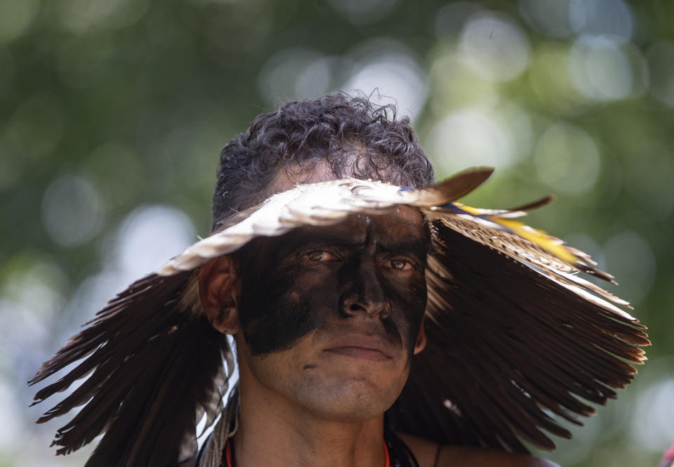 A Guarani Mbya man in traditional indigenous dress joins a protest on property being developed by the real estate company Tenda to make way for apartment buildings, next to his community's land in Sao Paulo, Brazil, Thursday, Jan. 30, 2020. The tension between a builder with projects in nine Brazilian states and a 40-family indigenous community is a microcosm of what’s playing out elsewhere in the country. (AP Photo/Andre Penner)