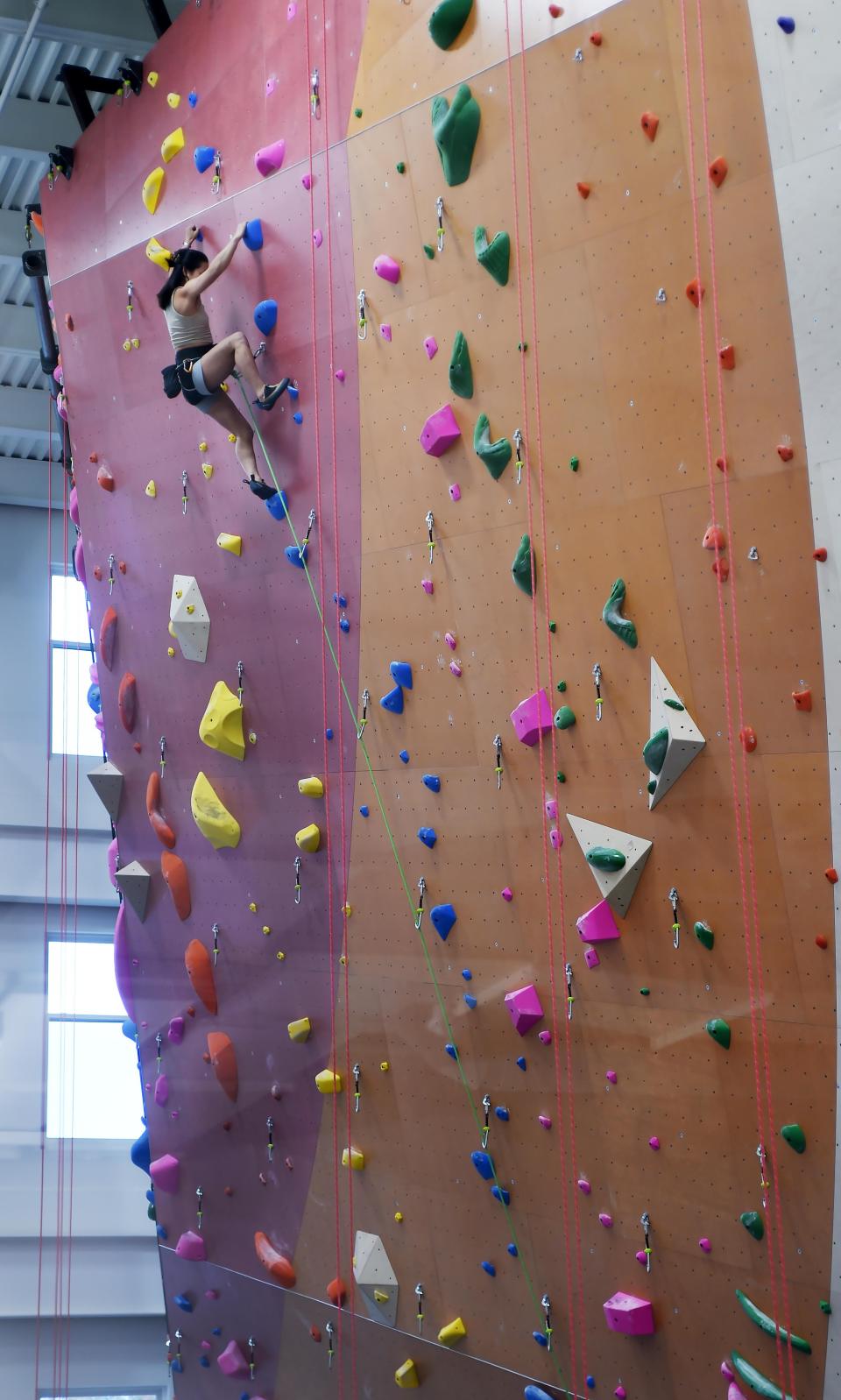 At Ascend Erie climbing gym, as seen through a second-floor window, employee Chelsea Huddleston, 26, checks routes on the 52-foot wall in Erie on Nov. 2, 2023.