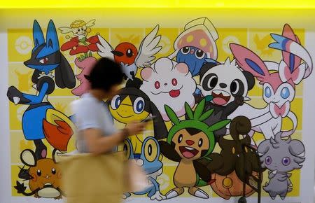 A woman using a mobile phone walks past a shop selling Pokemon goods in Tokyo, Japan July 20, 2016. REUTERS/Toru Hanai