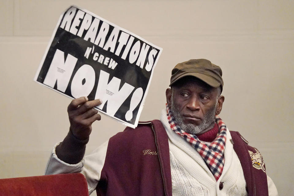 Morris Griffin holds up a sign during a meeting of California's reparations task force in Oakland on Dec. 14, 2022. (Jeff Chiu / AP file)