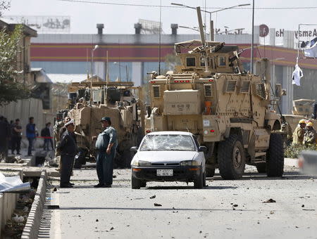 Afghan security forces talk next to a damaged civilian car at the site of a suicide car bomb blast in Kabul, Afghanistan, October 11, 2015. REUTERS/Omar Sobhani