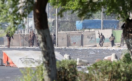 Members of the Iraqi security forces stand guard at a protest during a curfew, three days after the nationwide anti-government protests turned violent, in Baghdad