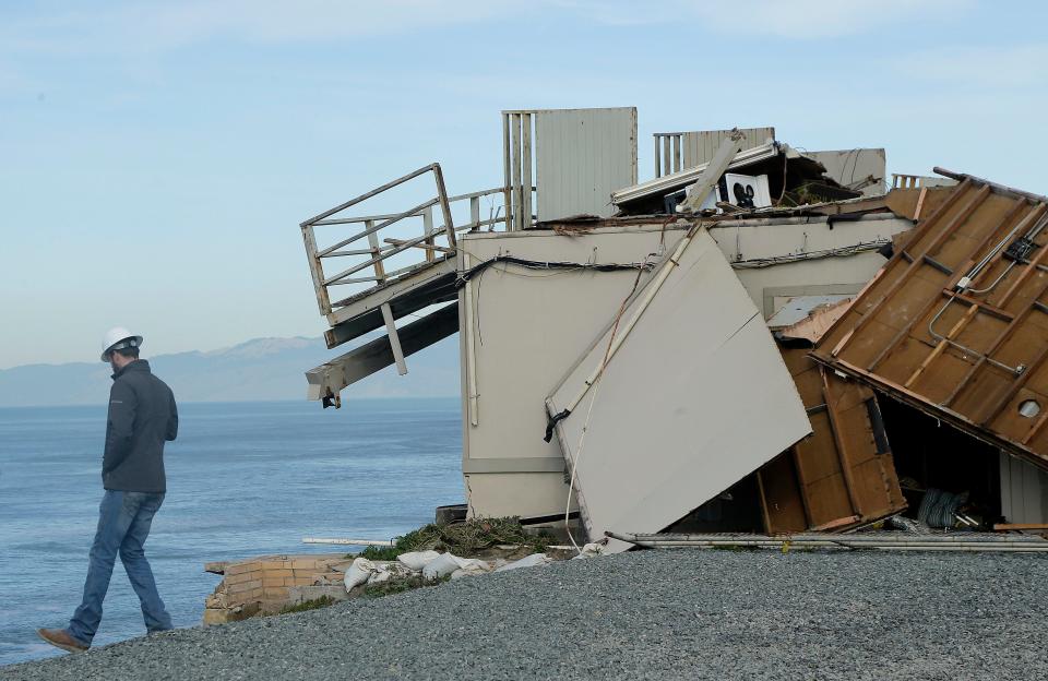 A worker looks over a cliff as demolition crews tear down an apartment building in Pacifica, Calif., Monday, Jan. 30, 2017. Storm-driven coastal erosion prompted city officials to mark the building as uninhabitable in 2016.