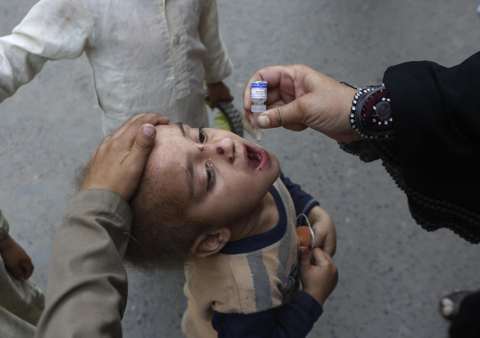 A health worker administers a polio vaccine to a child in Lahore, Pakistan, Monday, March 29, 2021. Despite a steady rise in coronavirus cases, Pakistan on Monday launched a five-day vaccination campaign against polio amid tight security, hoping to eradicate the crippling children's disease this year. (AP Photo/K.M. Chaudary)