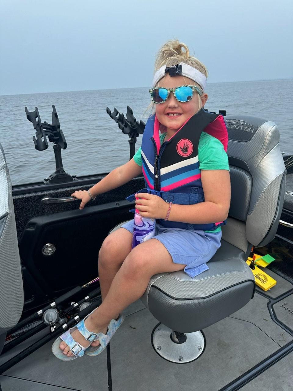 Henley Wollak, wearing a "mermaid-colored" life vest, rides aboard her dad's boat on Lake Michigan.