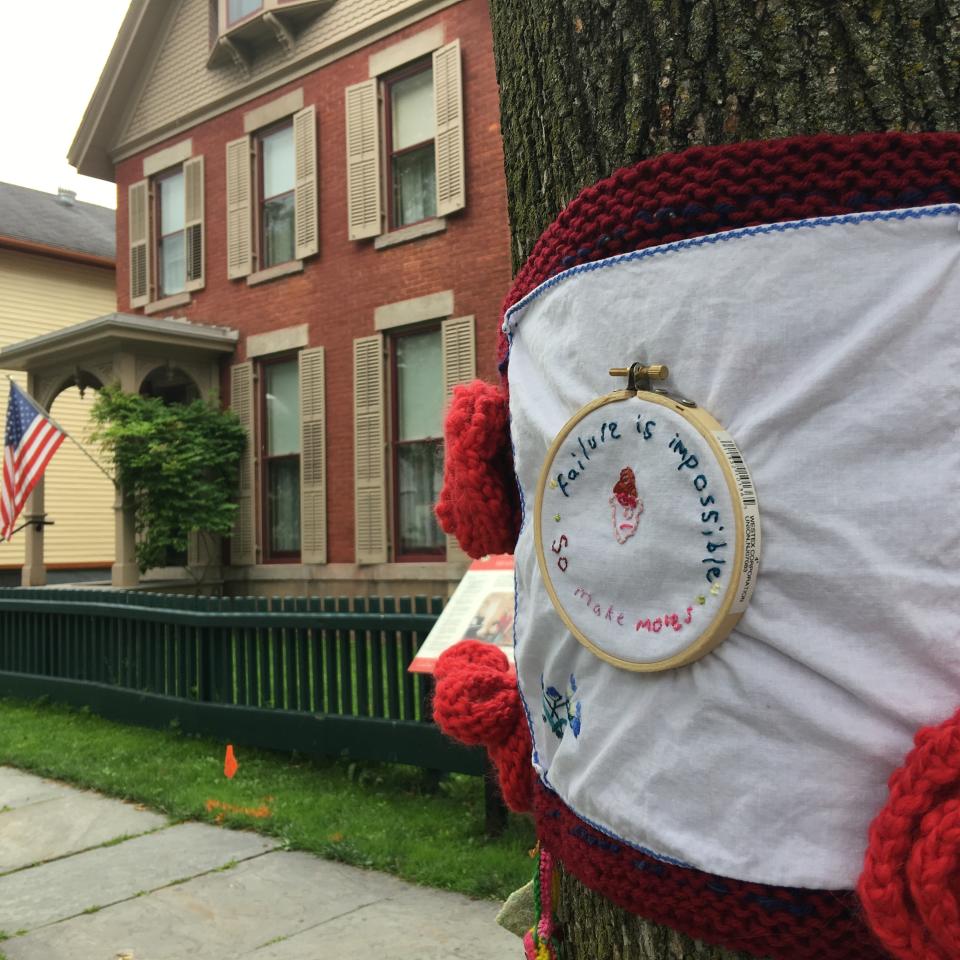 This July 2017 photo provided by Hinda Mandell shows an embroidery outside of Susan B. Anthony's historic home in Rochester, N.Y., installed by Mandell to coincide with the city's centennial celebration of women gaining the right to vote in New York State. The embroidery reads: "Failure is impossible so make moves." Knitters and crocheters call it yarn bombing. They're using fiber arts to make political statements, or maybe just to lift people's spirits. Experts say yarn bombing is part of a long tradition in which women use textile arts to agitate, excite or inspire. (Hinda Mandell via AP)