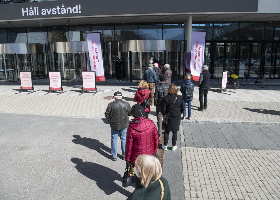 People queue to receive a COVID-19 vaccine, outside the Stockholmsmassan exhibition center turned mass vaccination center, in Stockholm, Sweden, Thursday April 8, 2021. (Fredrik Sandberg/TT News Agency via AP)