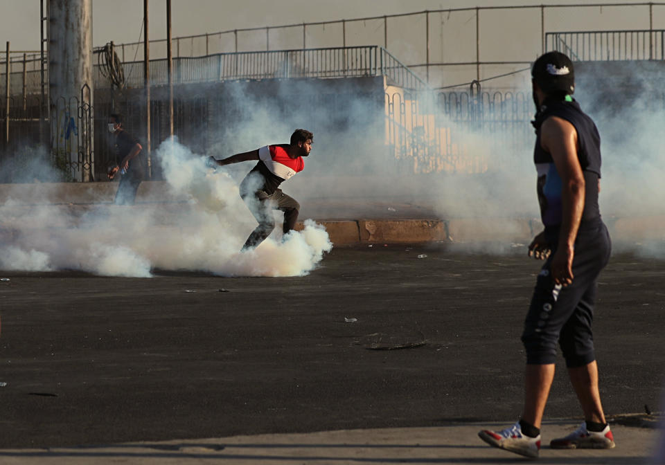 A protester throws back the smoke bomb back towards riot police during a demonstration in Baghdad, Iraq, Saturday, Oct. 5, 2019. The spontaneous protests which started Tuesday in Baghdad and southern cities were sparked by endemic corruption and lack of jobs. Security responded with a harsh crackdown, leaving more than 70 killed. (AP Photo/Hadi Mizban)